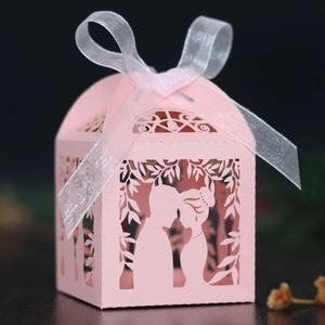 Detail of pink laser-cut wedding favor box featuring silhouette and white organza ribbon
