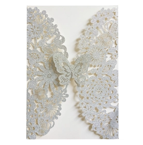 Macro detail of silver glitter laser-cut invitation card with floral and butterfly patterns