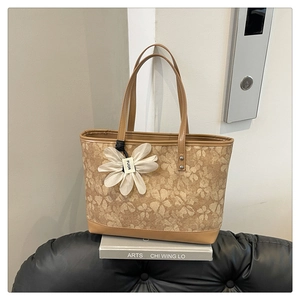 Close-up of vintage brown tote bag with floral embroidery and white daisy charm