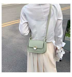 Photo en extérieur montrant le dos d'un sac besace vert clair avec détail de ruban