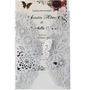 Detail view of laser-cut silver glitter wedding invitation with intricate butterfly design