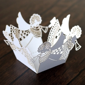Laser-cut white paper cupcake wrappers featuring delicate angel motifs for party decoration