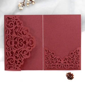 Macro shot of laser-cut burgundy pearlescent invitation with elegant floral details