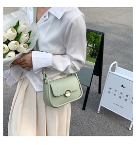 Détail du sac selle vert menthe avec boucle en émail blanc bordée d'or et fine bandoulière