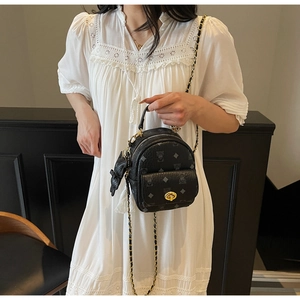 Detail einer Mini-Eimertasche in Schwarz mit Bärchenmuster und goldener Kette