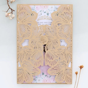 Detail of laser-cut gold wedding invitation with floral hollow pattern and pink rose card