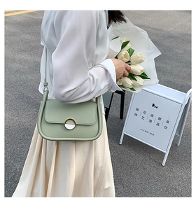 Détail du sac selle vert clair avec boucle dorée et accessoire élégant en ruban de soie
