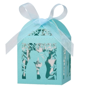 Detail of light blue laser-cut wedding favor box with ribbon bow and couple silhouette