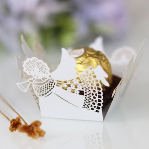 Close-up of laser-cut angel design on a white paper candy box with a chocolate inside