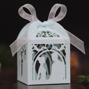 Detail of light blue laser-cut wedding favor box with ribbon on dark wood surface