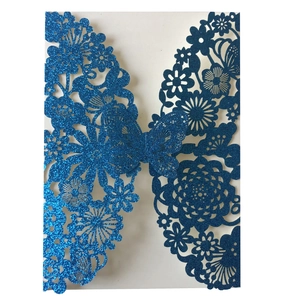 Macro view of blue glitter laser cut butterfly and floral patterns on invitation card
