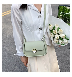 Détail du sac selle vert menthe avec boucle dorée ronde et ruban sur la bandoulière