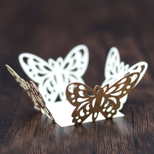 Detail of laser-cut butterfly cupcake wrapper in elegant white and gold lace design