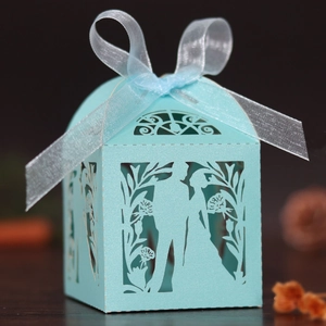 Close-up of laser-cut light blue wedding favor box with ribbon and floral silhouette