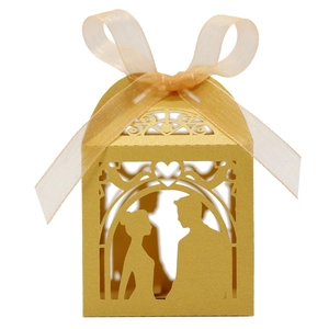 Detail of laser-cut gold wedding favor box featuring bride and groom silhouette with ribbon