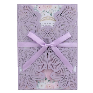Close-up of laser-cut lavender wedding invitation with pearl finish and satin ribbon