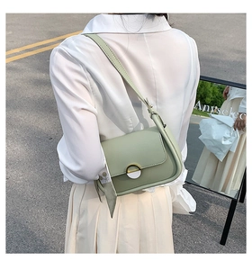 Détail du sac selle vert clair en cuir mat avec accessoire décoratif en foulard de soie