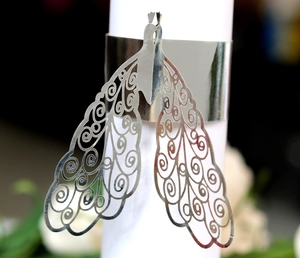 Close-up of silver hollow-out laser cut napkin ring with peacock feather pattern