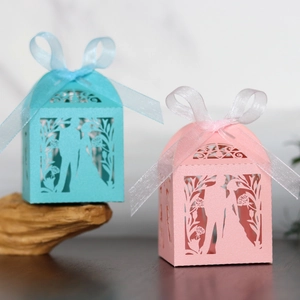 Detailed laser-cut wedding favors boxes in pink and blue with elegant ribbon bows