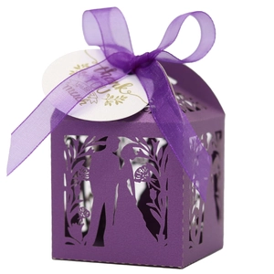 Détail de boîte cadeau violette découpée au laser avec silhouette de mariés et ruban