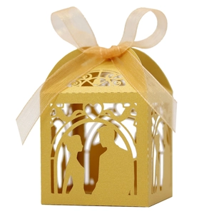 Detail of laser-cut gold wedding favor box with romantic couple silhouette and ribbon