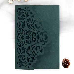 Detail of forest green laser-cut wedding invitation envelope with intricate lace patterns