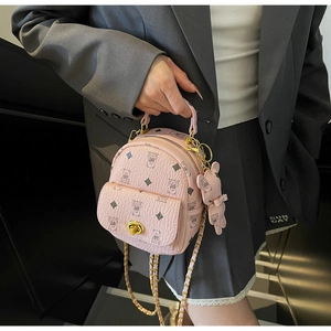 Detail eines rosa Mini-Rucksacks mit Litschi-Maserung und Bärenanhänger-Akzent