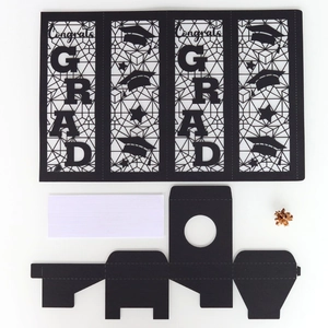 Flat lay of black graduation paper lantern DIY kit with Congrats and GRAD hollow cutouts