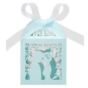 Detail of laser cut mint blue wedding favor box with romantic couple silhouette and ribbon