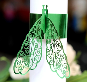 Macro view of green laser-cut peacock napkin ring with intricate filigree details