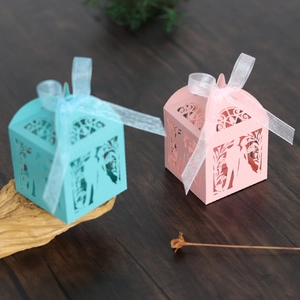 Detail of laser-cut candy boxes with ribbons on rustic wood table background