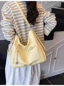 Large yellow tote bag with crocodile texture and adjustable shoulder strap worn by model