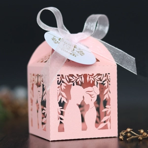 Détail macro d'une boîte à dragées rose découpée au laser avec ruban de soie blanc