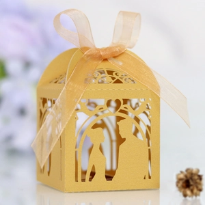 Detailed laser-cut pattern on yellow paper candy box with ribbon for wedding party favors