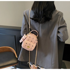 Detail eines rosa Mini-Rucksacks mit Bärenmuster und goldener Kette am Modell getragen
