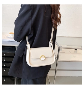 Détail du sac selle en cuir blanc cassé avec boucle dorée et bandoulière réglable pour femme