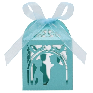 Close-up of laser-cut wedding favor box with romantic silhouette and blue ribbon