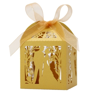 Detail of laser cut gold wedding favor box with ribbon and elegant silhouettes