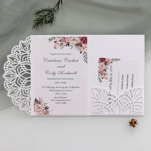 Detail of laser cut wedding invitation with floral insert cards and elegant lace pattern