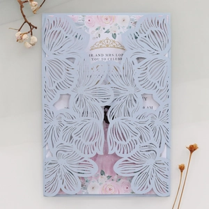 Macro shot of laser-cut floral wedding invitation with rose insert and golden crown detail