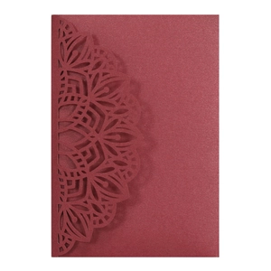 Macro shot of laser-cut mandala pattern on dark red pearlescent paper invitation card