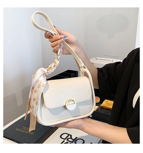 Détail du sac selle crème avec boucle métallique et foulard en soie sur la bandoulière