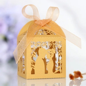 Macro shot of laser-cut gold wedding favor box with romantic couple silhouette and ribbon