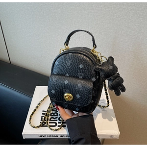 Detail eines schwarzen Mini-Rucksacks mit goldenem Drehverschluss und Bärenmuster