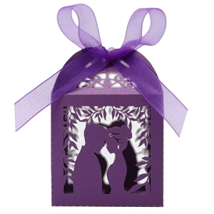 Detail of laser-cut purple wedding candy box with bride and groom silhouette and ribbon bow