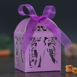 Detail of purple laser-cut wedding favor box with romantic couple pattern and ribbon bow