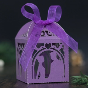 Detail of laser-cut purple gift box with couple silhouette and matching ribbon bow