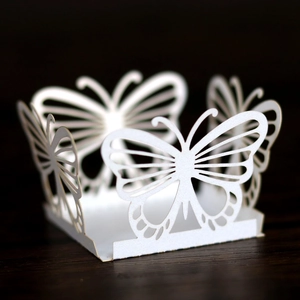 Detail showing laser-cut white paper butterfly favor box with intricate hollow patterns