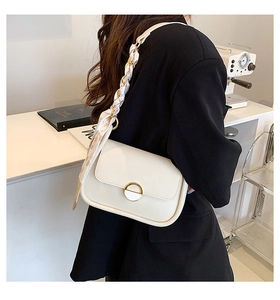 Détail du sac selle crème avec boucle dorée et décor de poignée en foulard de soie