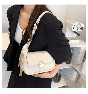 Détail du sac selle blanc cassé avec foulard à pois décoratif et fermoir magnétique